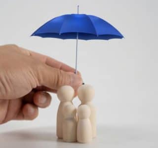 Main tenant un parapluie bleu au-dessus d'une famille en bois, symbolisant la protection des consommateurs contre le démarchage téléphonique