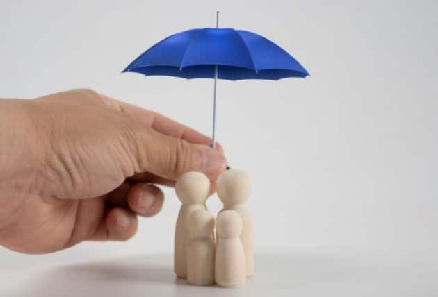 Main tenant un parapluie bleu au-dessus d'une famille en bois, symbolisant la protection des consommateurs contre le démarchage téléphonique