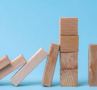 Effet domino stoppé par un mur de cubes en bois, symbolisant les 10 ans de protection contre les rattrapages excessifs de facturation d'énergie